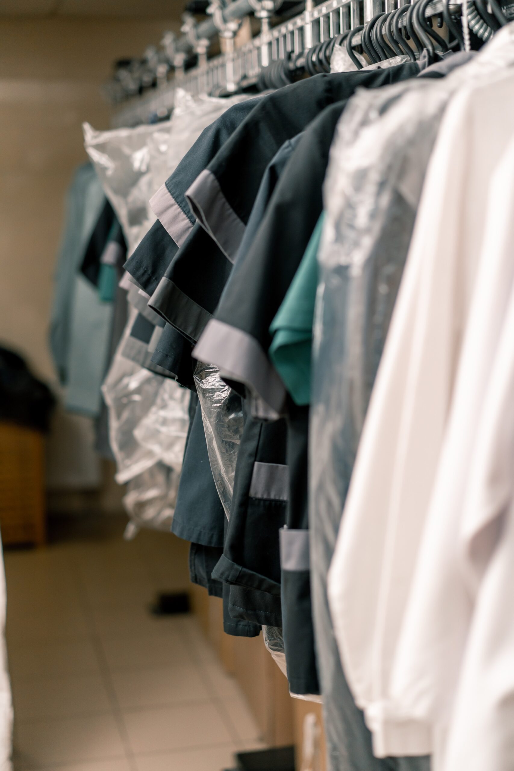 Clothing on hangers covered with plastic in a closet.